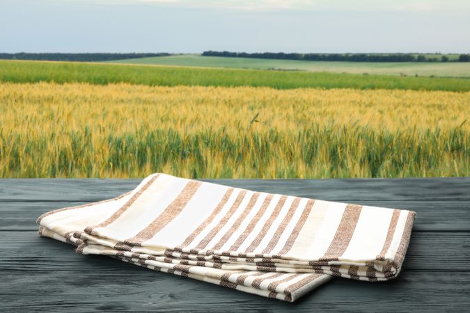 Wooden table with towel against field. Harvest season