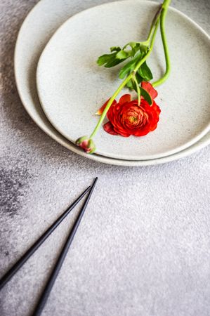 Rustic table setting with red buttercup flowers on grey plate