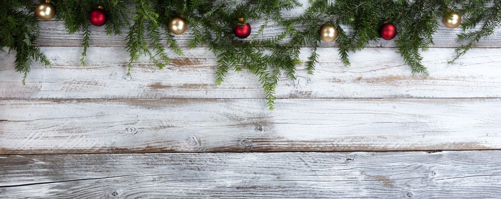 Real fir branches with gold and red ball ornaments on rustic wood for the Christmas or New Year holiday background