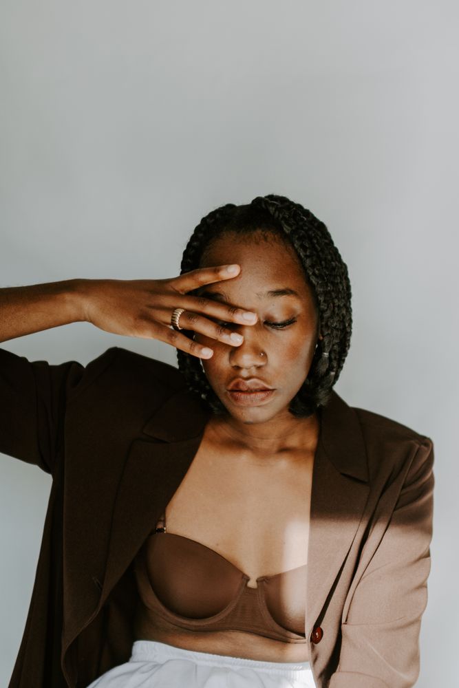 Woman in brown blazer against light wall