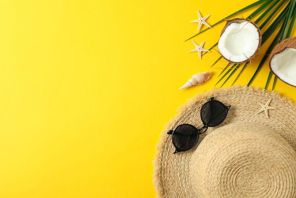 Straw hat, sunglasses, starfishes, coconuts and palm leaf on color background space for text and top view. Summer vacation backdrop