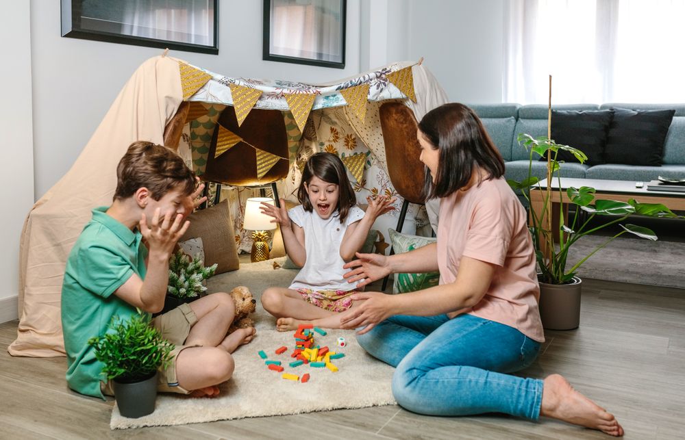 Happy family laughing and shouting together as a tower of wooden stacking piece game falls