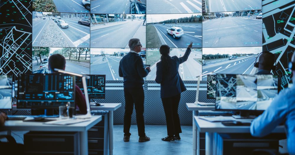 Two Diverse Male and Female Software Engineers Discuss Live Analysis Feed with City Road and Traffic Updates.