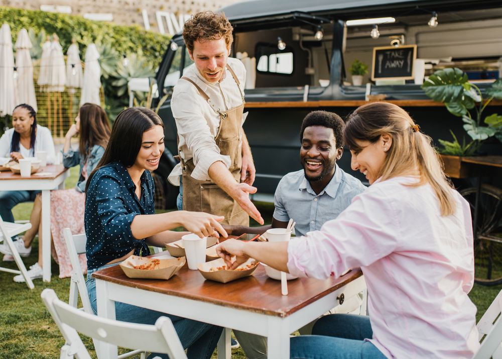 Multiracial people having fun eating at food truck outdoor