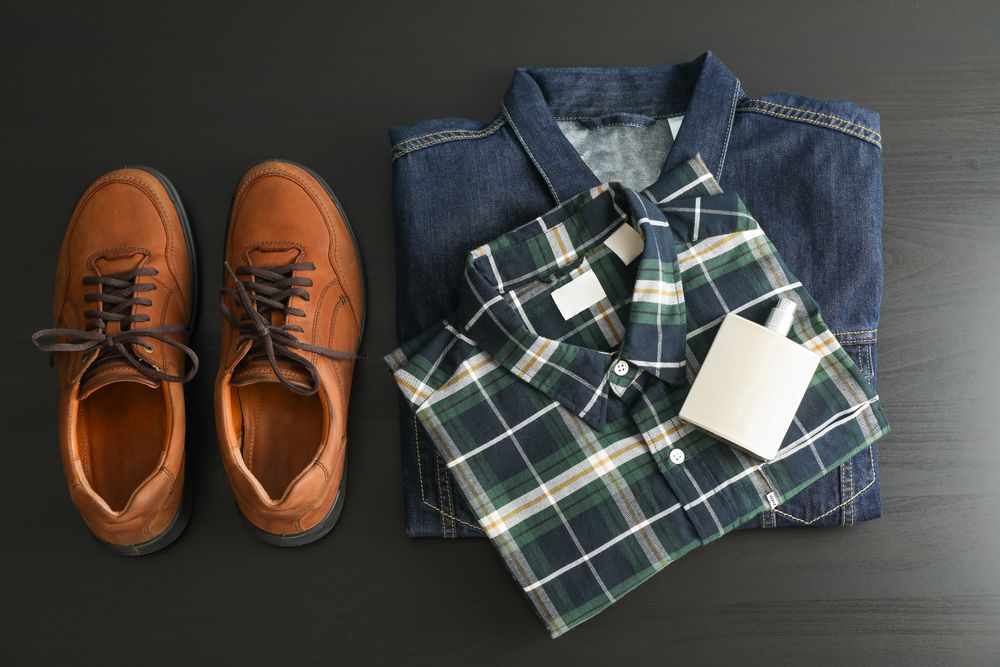 Flat lay composition with denim jacket, shirt, perfume and shoes on table
