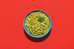 Pasta with pesto sauce, top view on a red background