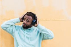 Optimistic Black hipster listening to music with headphones
