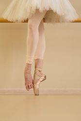 Ballet dancer at barre, one foot in pointe shoes