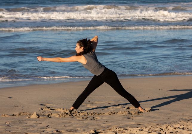 Young woman dancing and posing near water on shore