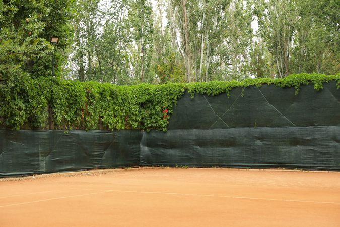 Clay tennis court with green fence, space for text