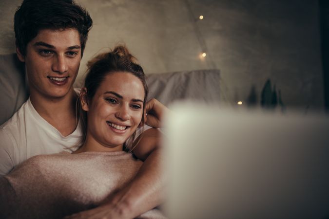 Affectionate couple watching video on laptop in bedroom