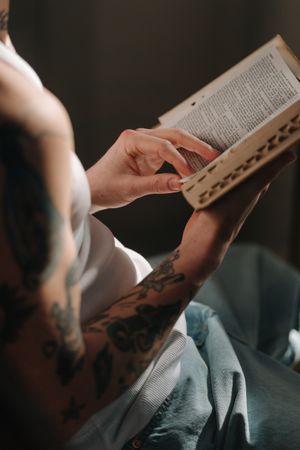 Cropped image of tattooed man reading a book