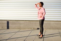 Female in modern business suit with hand protecting her eyes from the sun