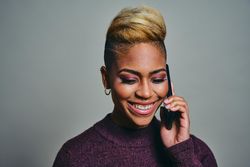 Smiling Black woman speaking on a cell phone while looking down