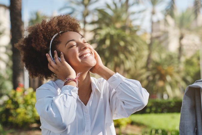Cheerful Black female listening to music on street