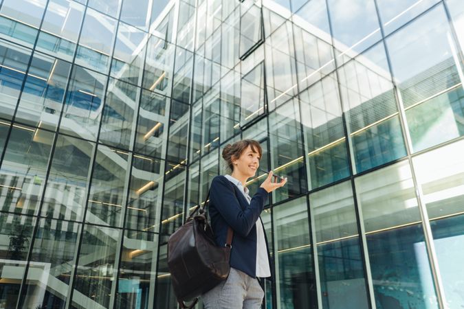 Smiling entrepreneur browsing smartphone outside office building