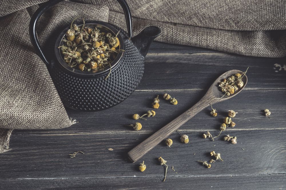 Spoonful of dried chamomile on wooden table