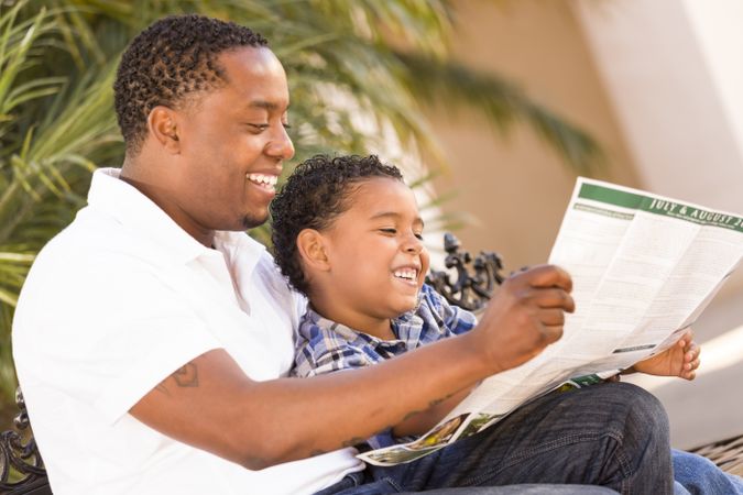 Father and Son Reading In Park Outside