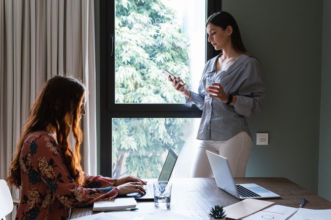 Positive colleagues working on laptop in light workspace