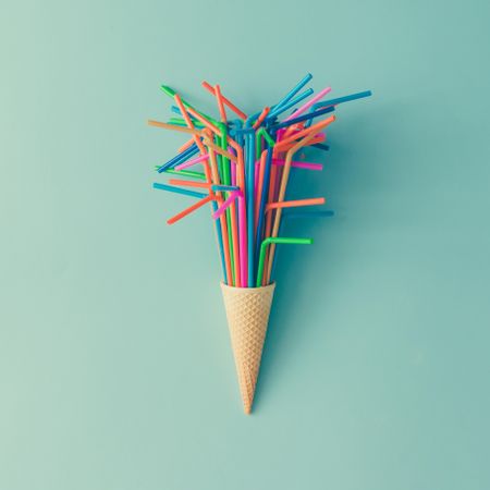Ice cream cone with straws on light blue background