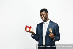 Smiling Black man holding a present wrapped in gold paper and a credit card 0P1Vl5