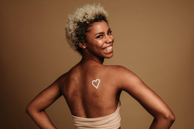 Close up of happy Black woman with a heart painted on back