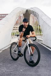 Cheerful man with bicycle standing on footbridge