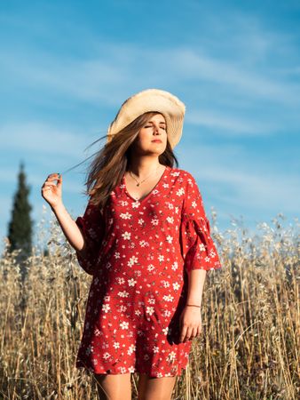 Happy dreamy woman standing among high grass