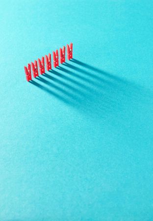 Red clothes pins and shadows on aqua background