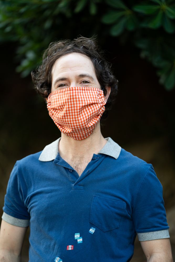 Portrait of smiling man wearing PPE mask outside