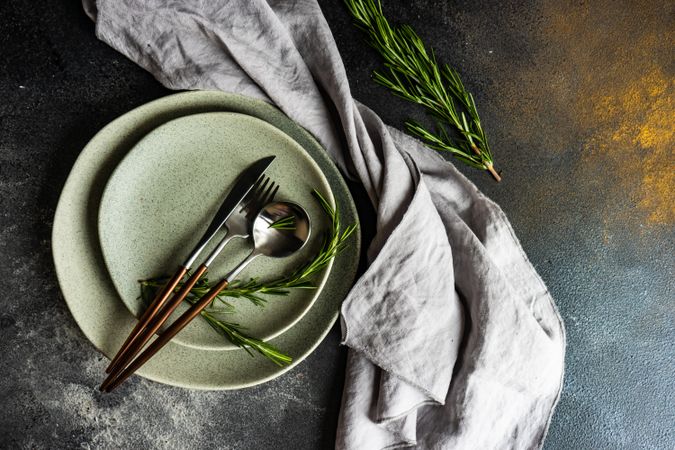 Top view of grey plate set with fresh rosemary