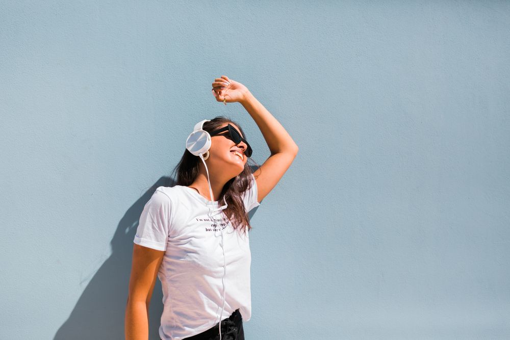Cheerful casual woman in sunglasses standing on city street