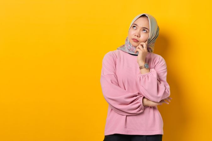 Muslim woman in headscarf looking up in deep thought