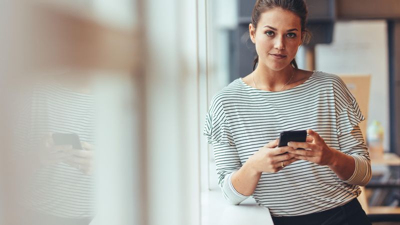 Woman taking break from work standing with cell phone in hand