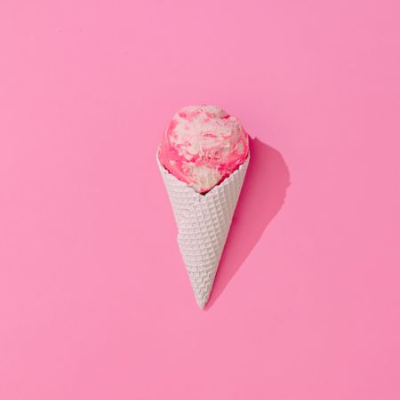 Waffle cone of pink ice cream on pink background