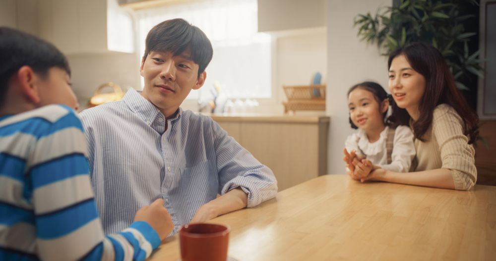 Portrait of Happy Small Korean Family Talking Together in Their Sunny Home.