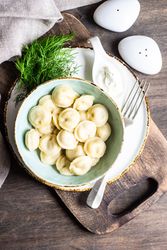 Top view of bowl of hearty Russian dumplings with salt and pepper shakers