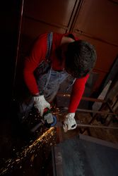 Master cutting metal plank by angle grinder