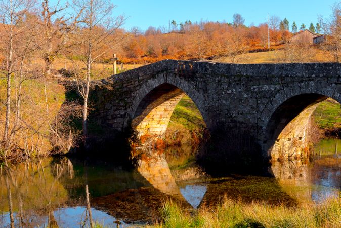 Old bridge over calm river in autumn countryside