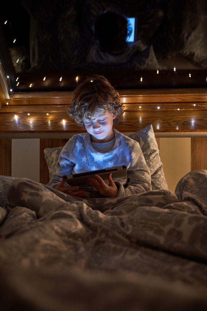 Boy playing game on tablet in dark bedroom