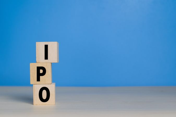 IPO letter text or initial public offering words on wooden blocks isolated on blue background. copy space