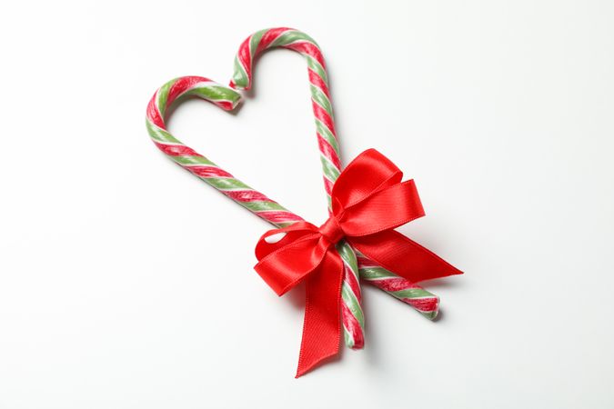 Sweet candy canes with bow on plain background, space for text