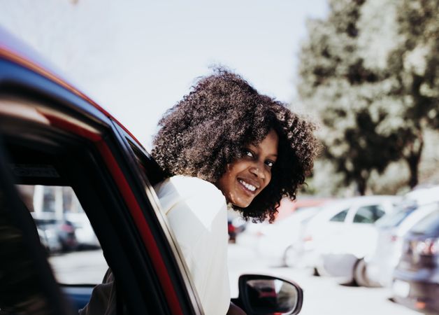 Woman with afro hair peeking out of the car .