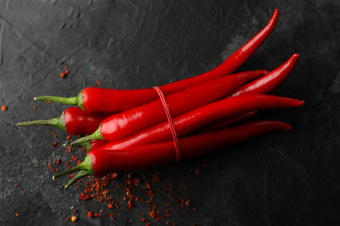 Tasty chilli peppers on dark cement background
