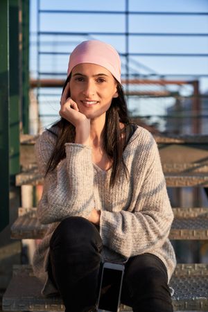 Smiling young woman sitting on metal stairs in city