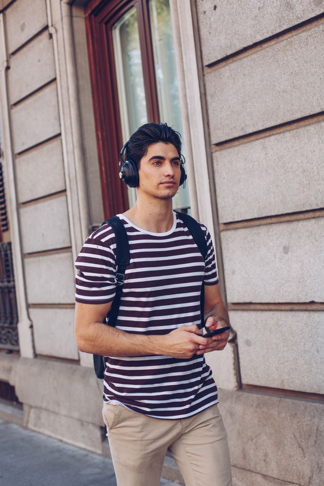 Young man with headphones and smartphone walking outdoors