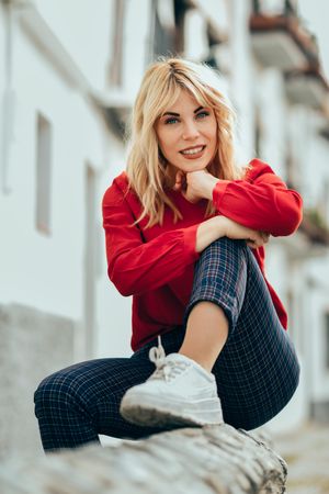 Calm blonde female with red shirt sitting outside, vertical