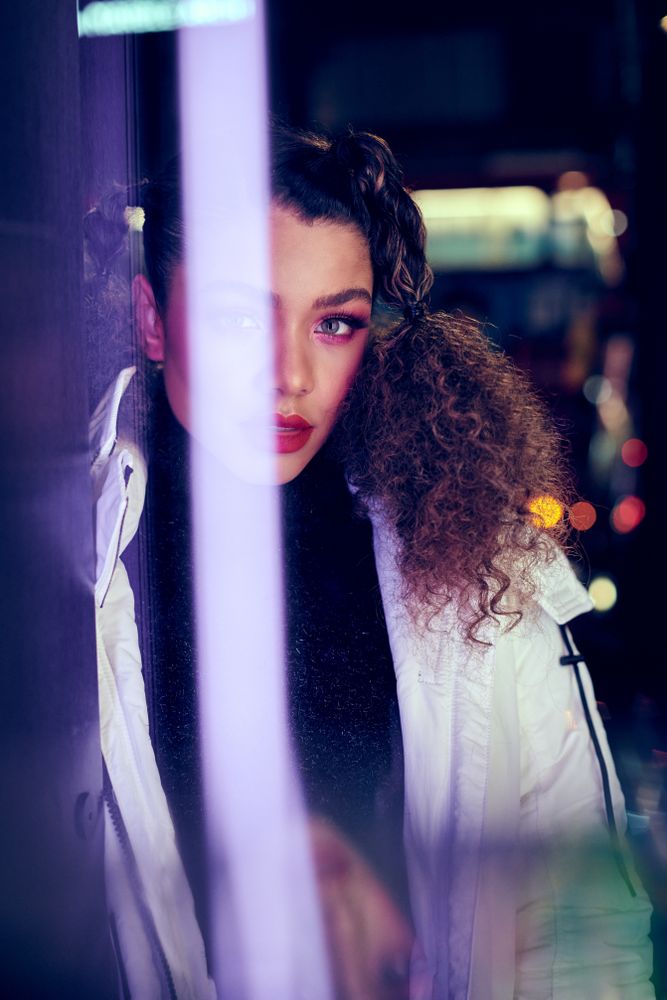 Young woman looking at camera through a purple light flare