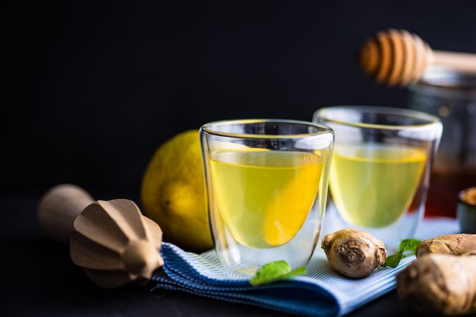 Side view of detox shots on napkin with lemon, ginger and mint on napkin