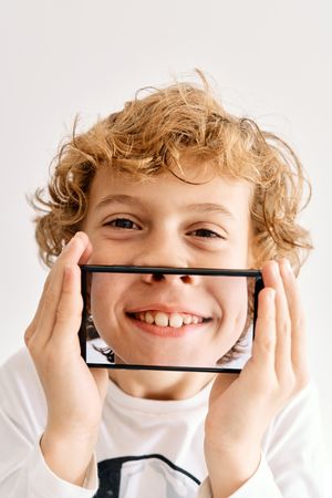 Child posing with his mobile phone and photos made of parts of his face